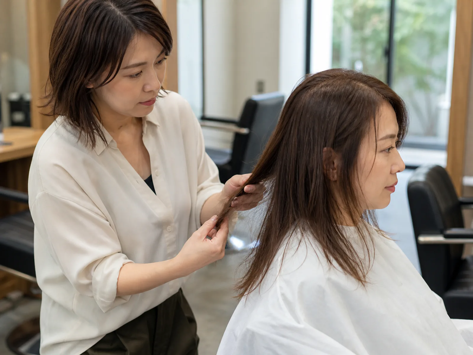 Professional consultation before a body-wave perm where a stylist evaluates fine hair condition.