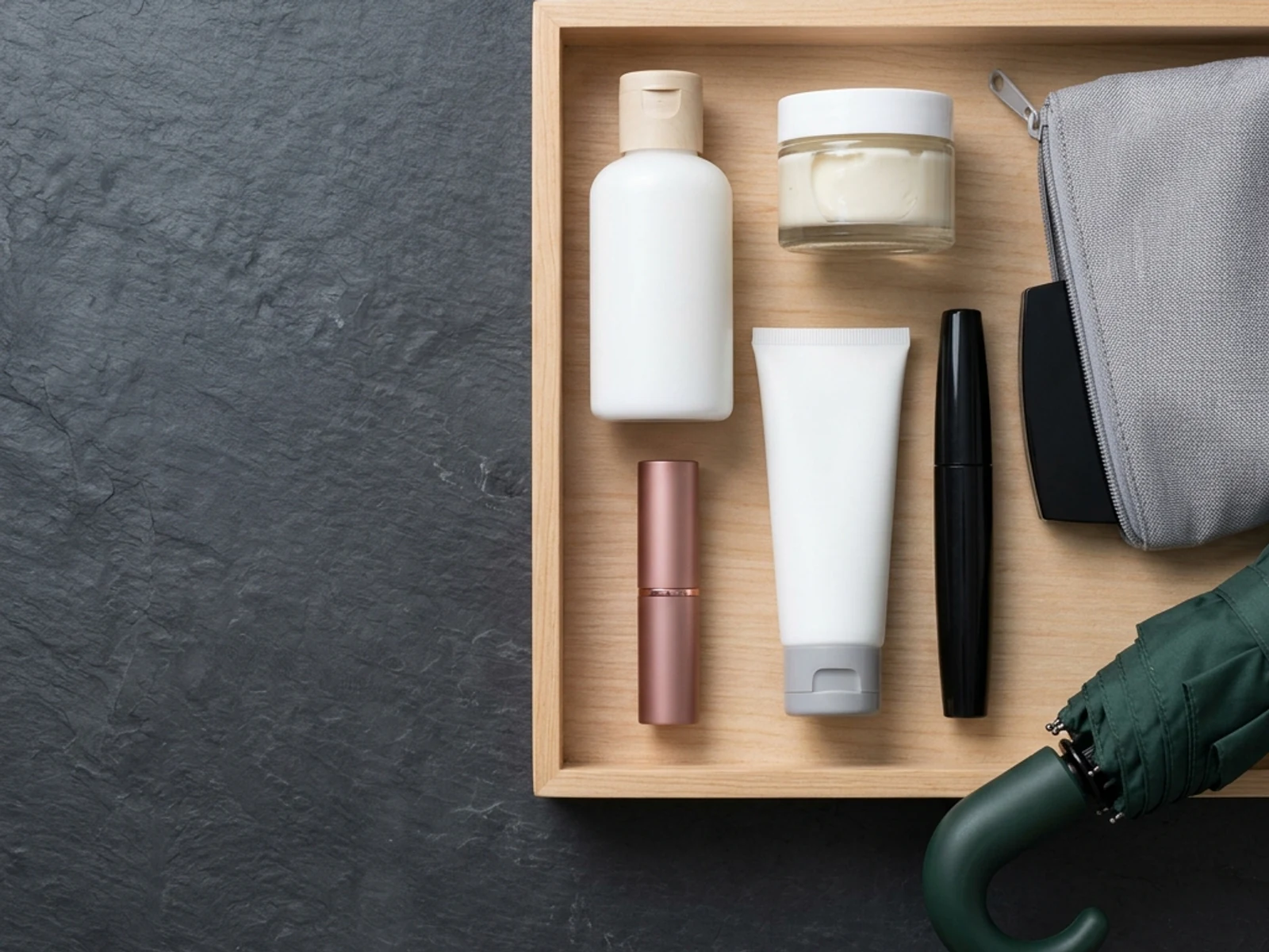 Skin, lip and makeup travel items arranged with a compact umbrella