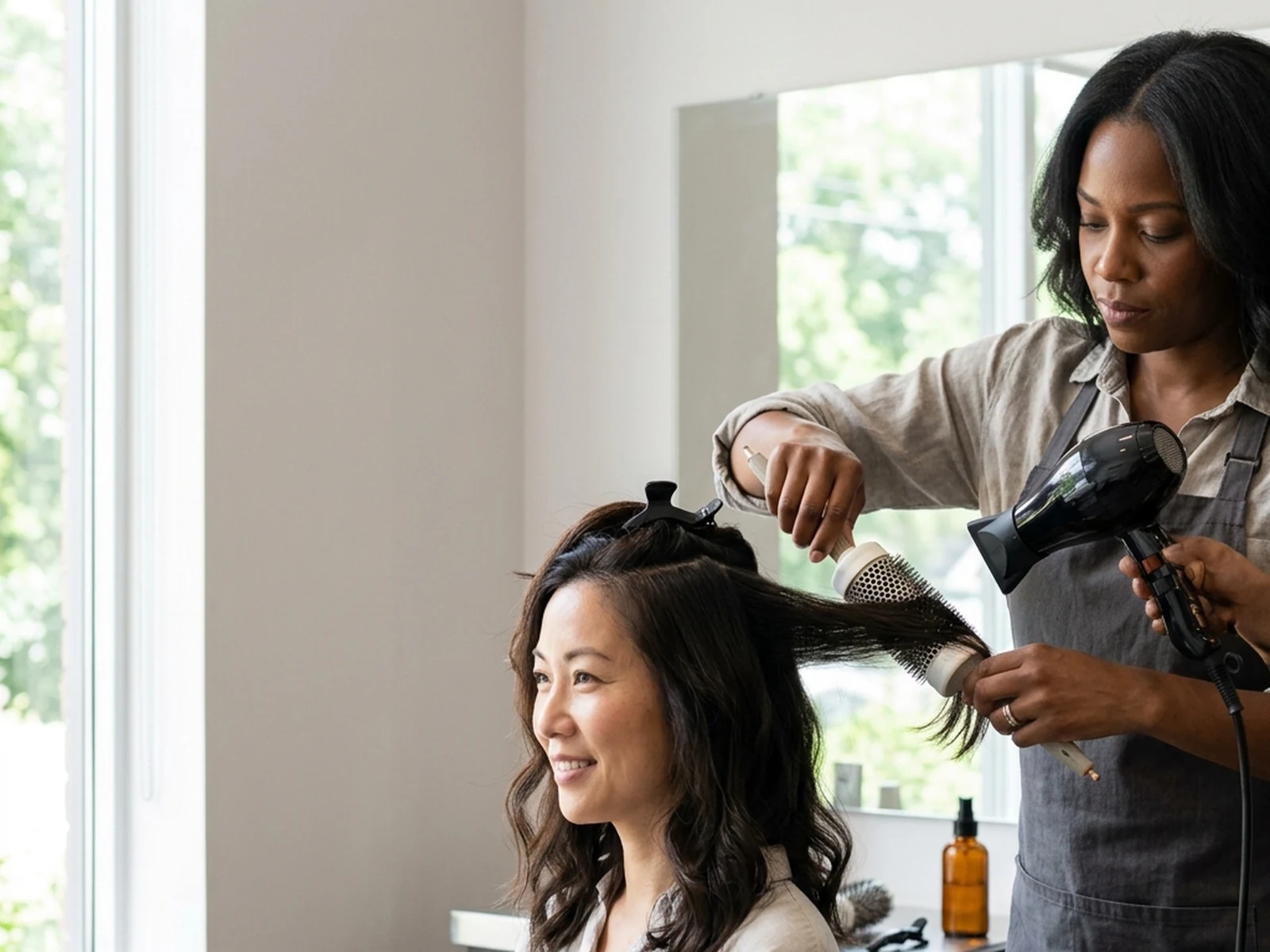 Stylist finishing a humidity-resistant blowout on textured hair